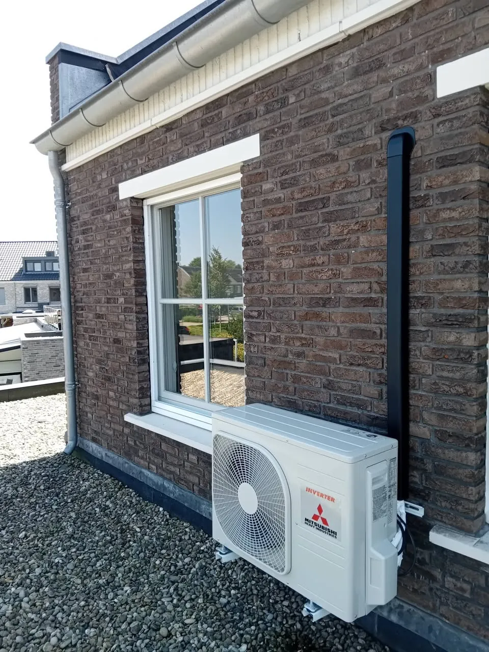 Airco buitenunit op wandbeugels aan een bakstenen gevel