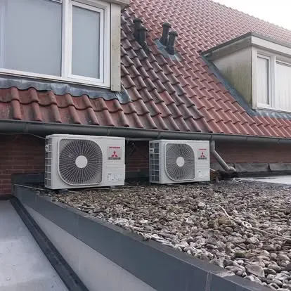 Buitenunits opgehangen onder de dakgoot van een woning